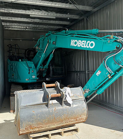 Excavator and attachment fitting snugly into a Store It Safe storage unit.